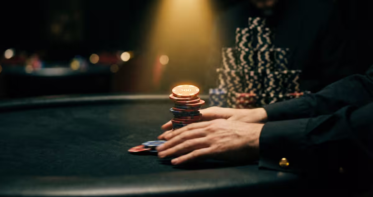 Stack corto de fichas junto a cartas en mesa de torneo